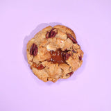 Salted Caramel Pecan New York Cookie with toasted pecans and gooey salted caramel center on a purple background.